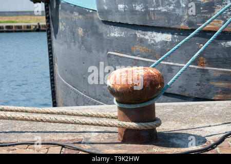 Rusty bollard con blu e grigio corda intorno ad esso Foto Stock