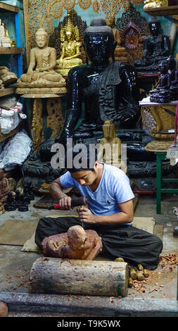 Mandalay, Myanmar - Il 9 febbraio 2017. Un uomo non identificato scalpelli legno in una scultura al negozio di souvenir Mandalay, Myanmar. Foto Stock