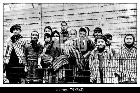 AUSCHWITZ I BAMBINI DETENUTI bambini carcerati indossando divise a strisce guardare fuori da dietro un filo spinato nella famigerata WW2 nazista di morte-camp Auschwitz Polonia meridionale. Seconda Guerra Mondiale Foto Stock