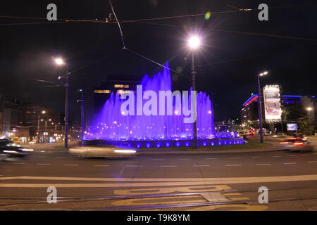 Slavija quadrato, cerchio di traffico nel centro di Belgrado di notte con fontana di blu. Foto Stock