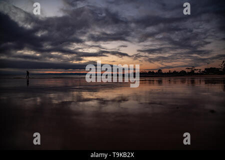 Spiaggia di riflessione del sorgere del sole in Devonport Tasmania, lone walker Foto Stock