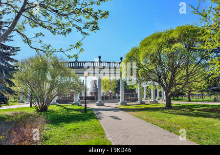 Novokuznetsk, Russia - 19 Maggio 2019: Primavera vicolo del parco cittadino per la vecchia fontana con il bianco collonade intorno ad esso. Molla luminoso paesaggio con i giovani Foto Stock