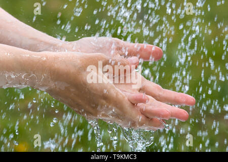 Donna lavando le mani sotto la pioggia, primo piano Foto Stock