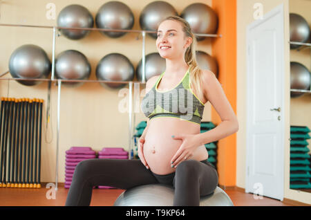 Yoga per donne in stato di gravidanza. Giovane bella ragazza incinta in sportswear fare yoga su fitball Foto Stock