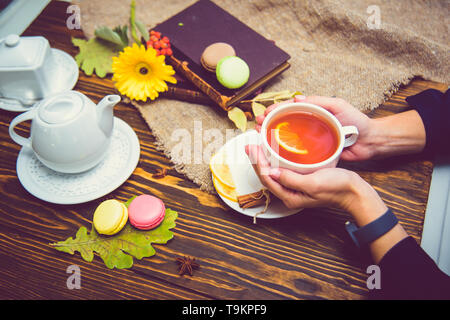 Una tazza di tè nero con limone riscalda i palmi della ragazza. In Coppa le palme Foto Stock