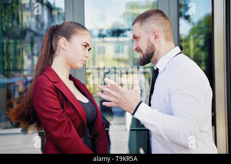 Noisy litigare con il capo dell'ufficio dipendente. Un uomo urla a una donna. Direttore di grido. Foto Stock