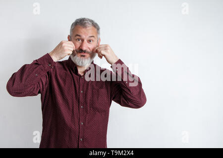 A mezza lunghezza Ritratto di un grave grey-haired uomo barbuto in una maglietta di borgogna su uno sfondo bianco. Foto Stock