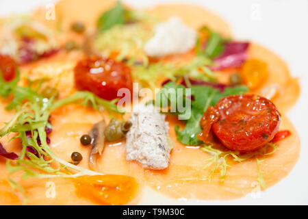 Carpaccio di salmone con salsa e sole asciugato i pomodori in piastra, close-up shot Foto Stock