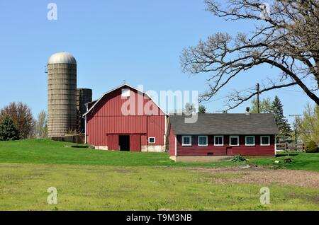 South Elgin, Illinois, Stati Uniti d'America. Un moderno granaio rosso circondato da silos e un capannone formano le strutture su una piccola agricolo di diffusione. Foto Stock