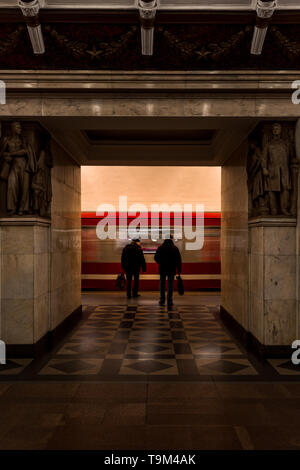 Passeggeri a piedi verso il rosso in arrivo alla metropolitana sulla piattaforma di Narvskaya stazione della metropolitana (linea Kirovsko-Vyborgskaya) (San Pietroburgo, Russia) Foto Stock