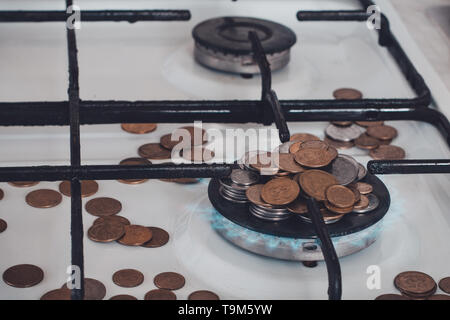 Blue Flames di gas naturale di masterizzazione da un fornello a gas su uno sfondo di monete. 2019 Foto Stock