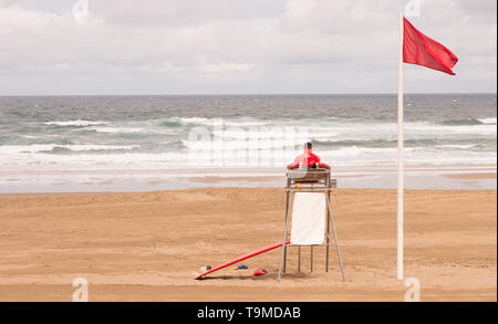 Un bagnino seduto sulla torre di sorveglianza, di fronte al mare Foto Stock