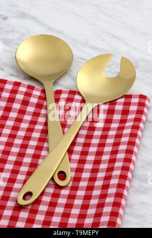 Alla moda e bellissimo golden cucchiaio e forchetta impostato in stile gingham placemat antichi e marmo di carrara Foto Stock