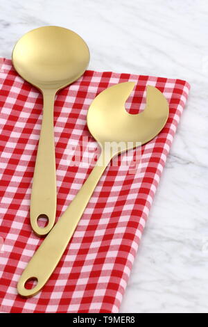 Alla moda e bellissimo golden cucchiaio e forchetta impostato in stile gingham placemat antichi e marmo di carrara Foto Stock