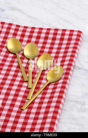 Alla moda e bellissimo golden cucchiaio e forchetta impostato in stile gingham placemat antichi e marmo di carrara Foto Stock