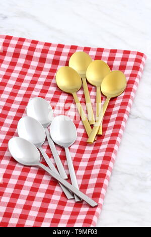 Alla moda e bellissimo golden cucchiaio e forchetta impostato in stile gingham placemat antichi e marmo di carrara Foto Stock