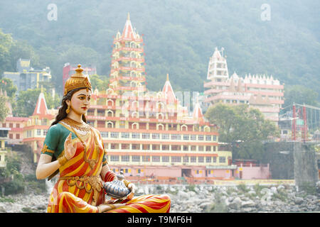 Splendida vista della statua di seduta dea Parvati sulla sponda del fiume Gange. Sfocato Trimbakeshwar tempio in background. Foto Stock