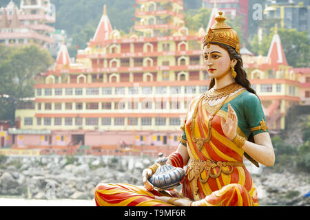 Splendida vista della statua di seduta dea Parvati sulla sponda del fiume Gange. Sfocato Trimbakeshwar tempio in background. Foto Stock