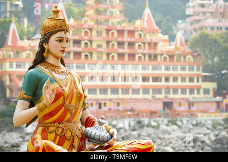 Splendida vista della statua di seduta dea Parvati sulla sponda del fiume Gange. Sfocato Trimbakeshwar tempio in background. Foto Stock