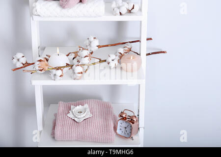 Vestiti caldi, cotone di fiori e candele su scaffali in prossimità della parete di luce Foto Stock