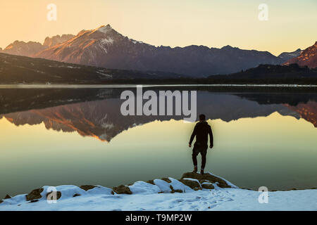 L'uomo raggiunge la roccia sopra il lago. La realizzazione in natura Foto Stock