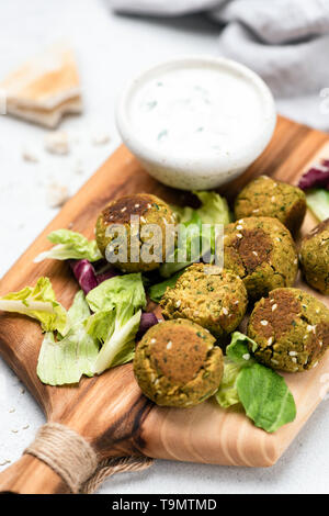 Falafel con salsa di yogurt servita sul tagliere di legno. Vista ingrandita, il fuoco selettivo Foto Stock