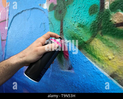 Mano azienda graffiti possono spruzzare sulla parete Foto Stock