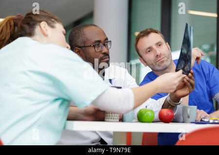 Team di medici in cerca di un xray mentre a pranzo Foto Stock
