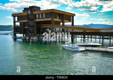 Un moderno porticciolo in legno edificio su palafitte a fianco della passerella galleggiante sul lago di Coeur d'Alene, con resort barche ormeggiate su un giorno di estate in Idaho Foto Stock