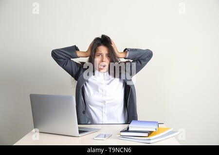 Sottolineato giovane donna seduta a tavola in office Foto Stock