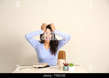 Urlando giovane donna seduta a tavola in office Foto Stock