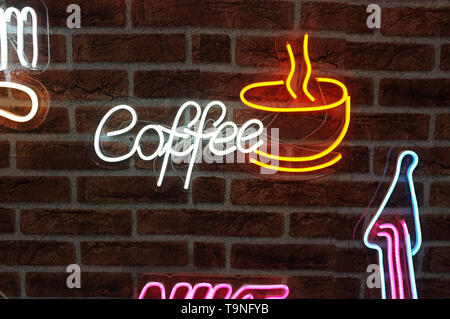 Insegna al neon dicendo di sfondo ' Caffè ' cartello appeso a una parete e illuminato brillantemente. Foto Stock