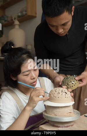 (190520) -- LONGQUAN, 20 maggio 2019 (Xinhua) -- Lin Song (R) e sua moglie Ji Jing discutere la realizzazione di incenso celadon spartifiamma nel suo studio di Longquan, est della Cina di Provincia dello Zhejiang, 20 maggio 2019. Nato nel 1993, Lin canzone è un nativo di Longquan, home alla Cina di migliore mercanzia celadon. Egli ha ricevuto la formazione professionale sia nella sua città natale e Jingdezhen, un altro importante hub di porcellana cinese. Lin ha avuto seguito anche altri artigiani celadon per anni prima di impostare un studio torna a casa nel 2014, concentrandosi sulla replicazione del classico incenso celadon bruciatori. Lin la collezione personale ha gr Foto Stock