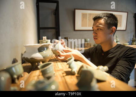 (190520) -- LONGQUAN, 20 maggio 2019 (Xinhua) -- Lin canzone controlla la sua collezione di classici Longquan mercanzia celadon nel suo studio di Longquan, est della Cina di Provincia dello Zhejiang, 20 maggio 2019. Nato nel 1993, Lin canzone è un nativo di Longquan, home alla Cina di migliore mercanzia celadon. Egli ha ricevuto la formazione professionale sia nella sua città natale e Jingdezhen, un altro importante hub di porcellana cinese. Lin ha avuto seguito anche altri artigiani celadon per anni prima di impostare un studio torna a casa nel 2014, concentrandosi sulla replicazione del classico incenso celadon bruciatori. Lin la collezione personale è cresciuto di oltre il 40 ce Foto Stock