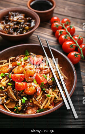 Piastra con saporiti spaghetti cinesi, i funghi e le verdure sul tavolo di legno, primo piano Foto Stock