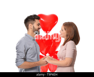 Amare giovane coppia con palloncini in forma di cuore su sfondo bianco. Celebrazione del giorno di San Valentino Foto Stock