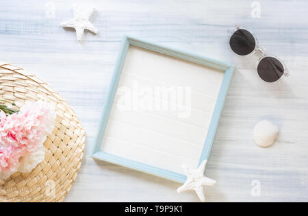 Vista superiore del summer blue picture frame con occhiali da sole e la conchiglia e la stella di mare e Fiore rosa decorazione su legno bianco table.vacanze estive Foto Stock