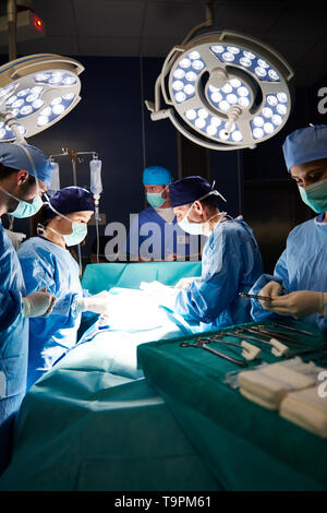 Buio in sala operatoria e chirurghi Foto Stock