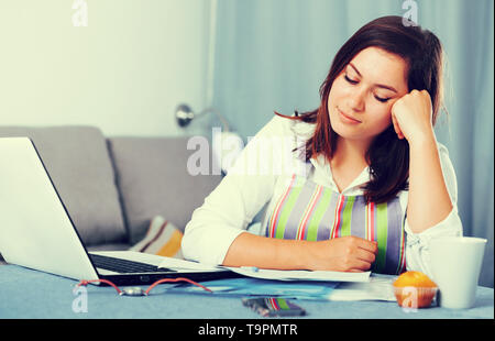 Giovane donna navigando attraverso utili suggerimenti per la cottura in Internet Foto Stock