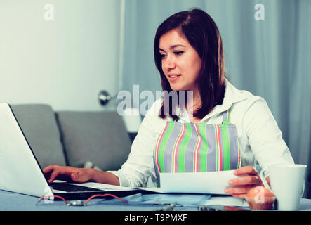 Giovane donna navigando attraverso utili suggerimenti per la cottura in Internet Foto Stock