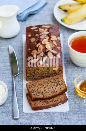 Banana, torta di carote, focaccia con il cioccolato e la tazza di tè sul grigio Sfondo tessili. Foto Stock