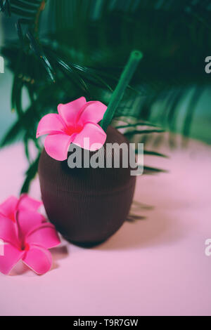 Noce di cocco cocktail con cannucce potabile e fiore tra palm tree foglie Foto Stock