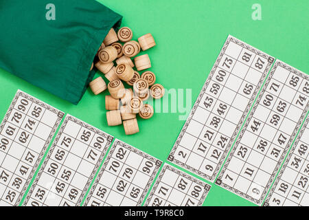 Lotto in legno Barili con borsa di stoffa e carte da gioco su sfondo verde. Gioco di bordo del lotto. Vista dall'alto. Foto Stock