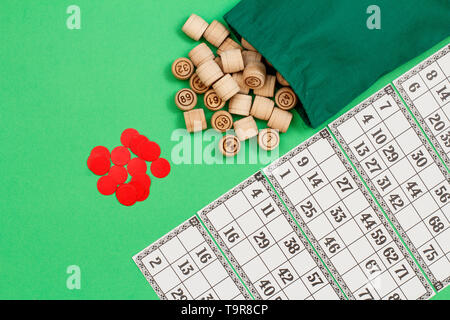 Lotto in legno Barili con borsa di stoffa, gioco di carte e chip rossi su sfondo verde. Gioco di bordo del lotto. Vista dall'alto. Foto Stock