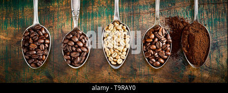 Assortimento di diversi caffè tostato e macinato fagioli visualizzati in argento vintage cucchiai in un panorama banner su legno rustico Foto Stock