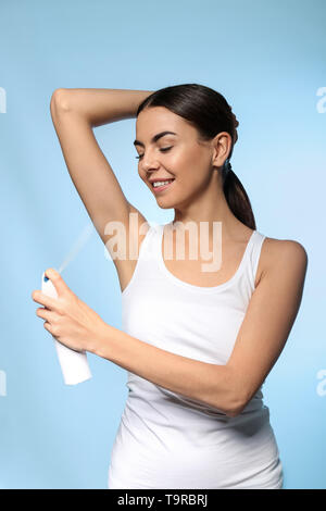 Giovane donna con deodorante sul colore di sfondo Foto Stock