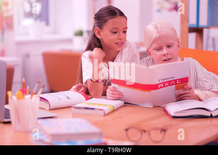 Due graziosi bambini la lettura di un libro cinese Foto Stock