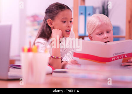 Due studenti cinesi di lettura cartella di lavoro alla scuola. Foto Stock