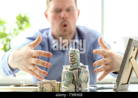 Mani maschio grabbing Big fat vaso pieno della valuta statunitense come gesto di avidità Foto Stock