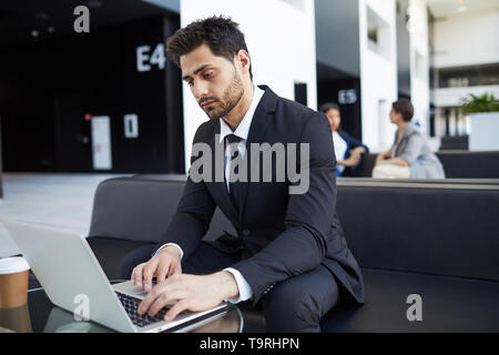 Razza mista manager esaminando i dati sul computer portatile Foto Stock